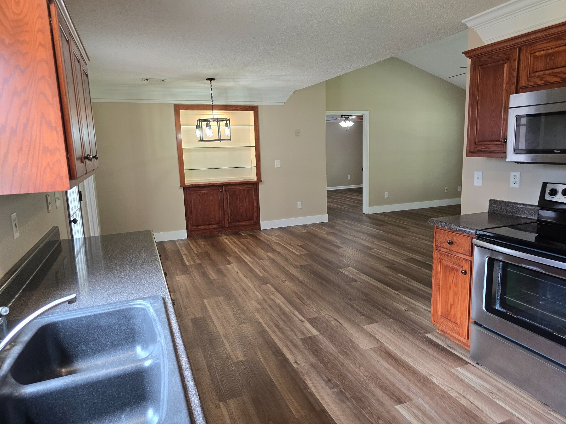 Kitchen with sink, wood cabinets, stainless-steel refrigerator, range, and microwave