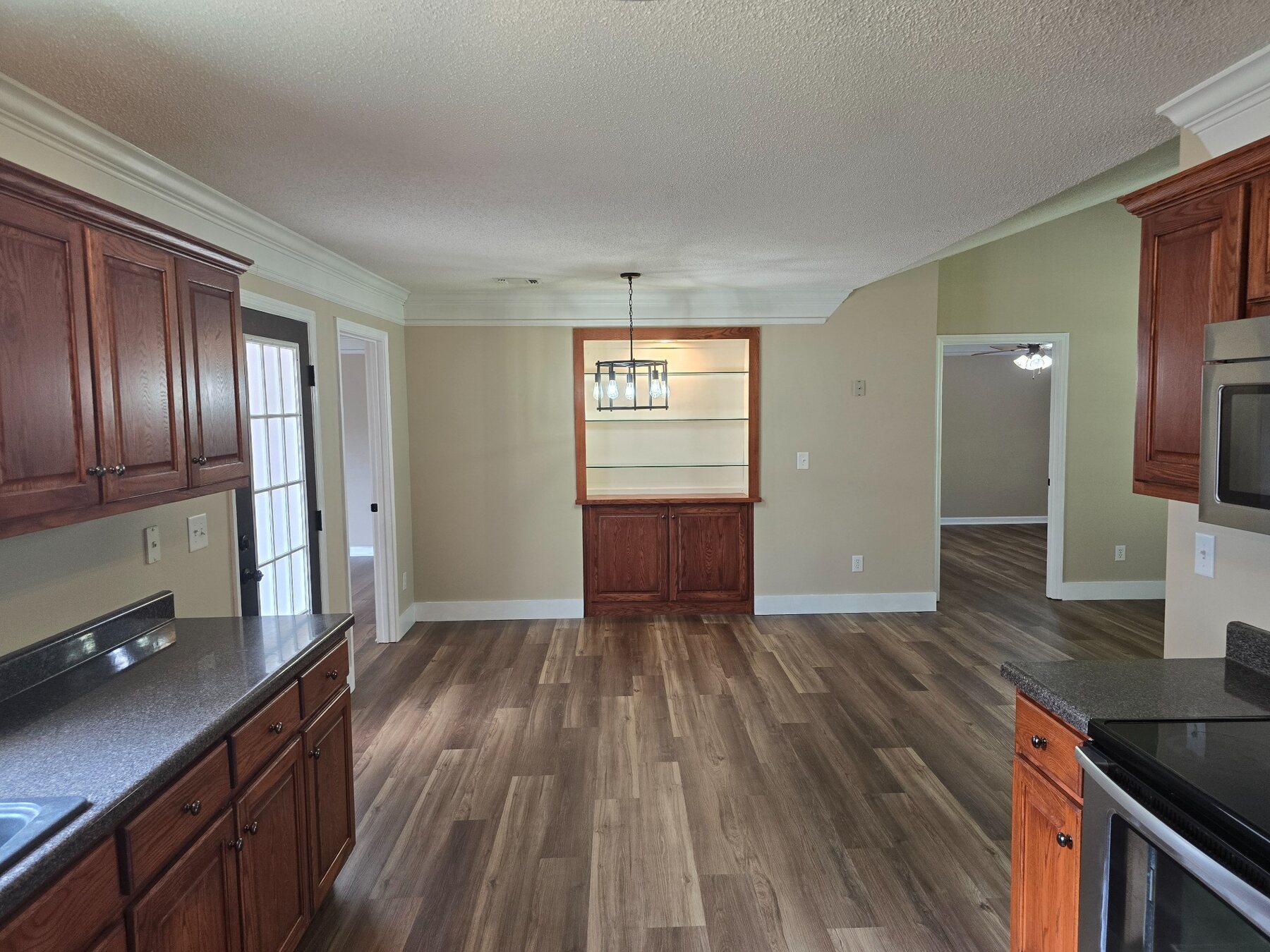 Kitchen view toward built-in display cabinet and adjoining room