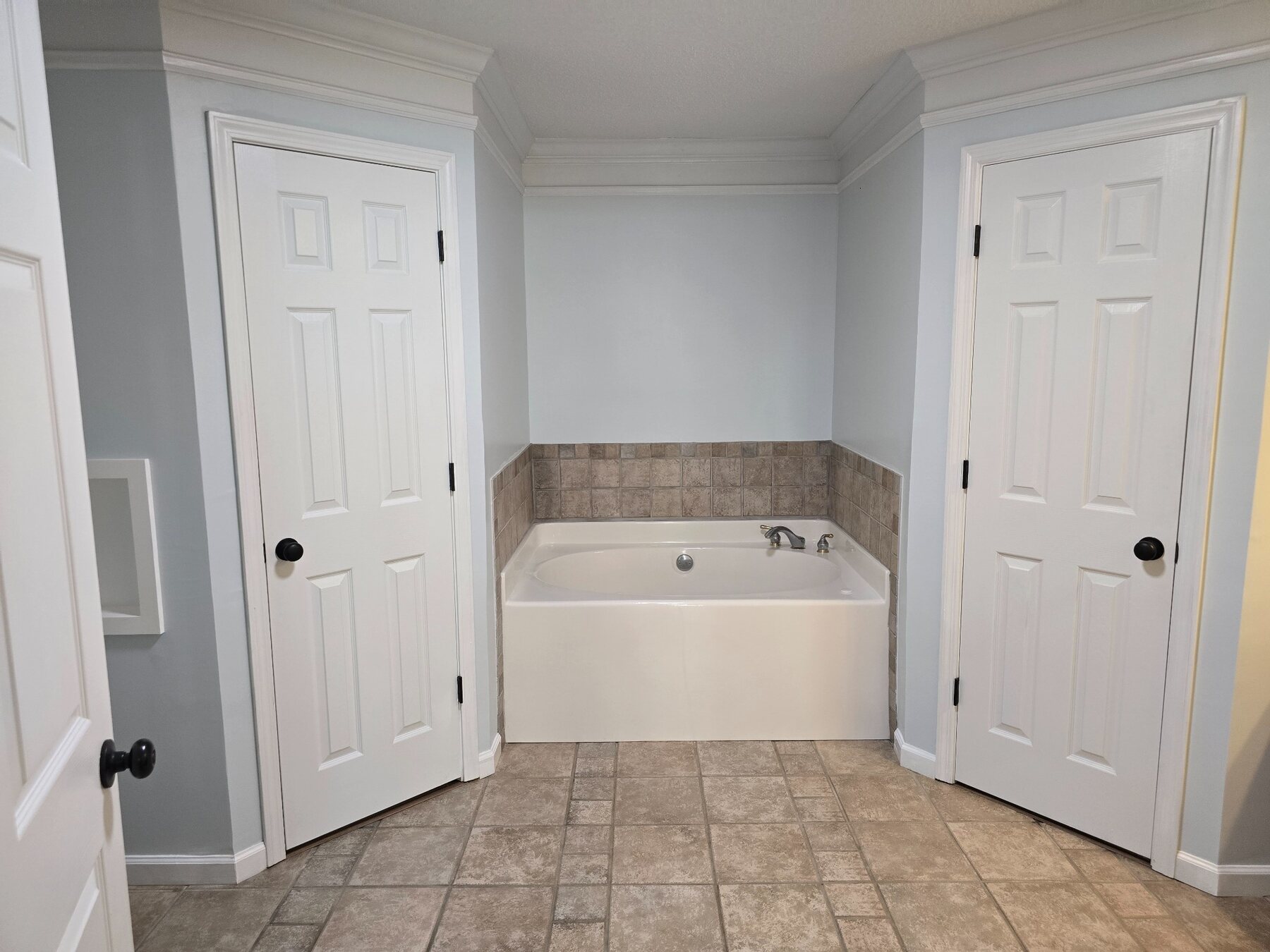 Bathroom with soaking tub and doors to adjoining spaces