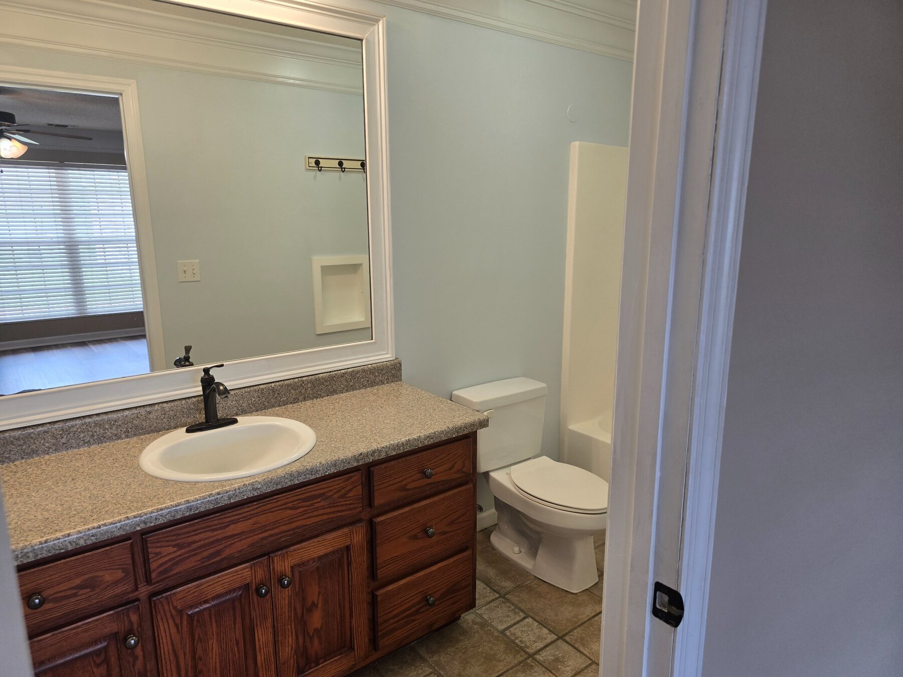 Bathroom with wood vanity, large mirror, and toilet