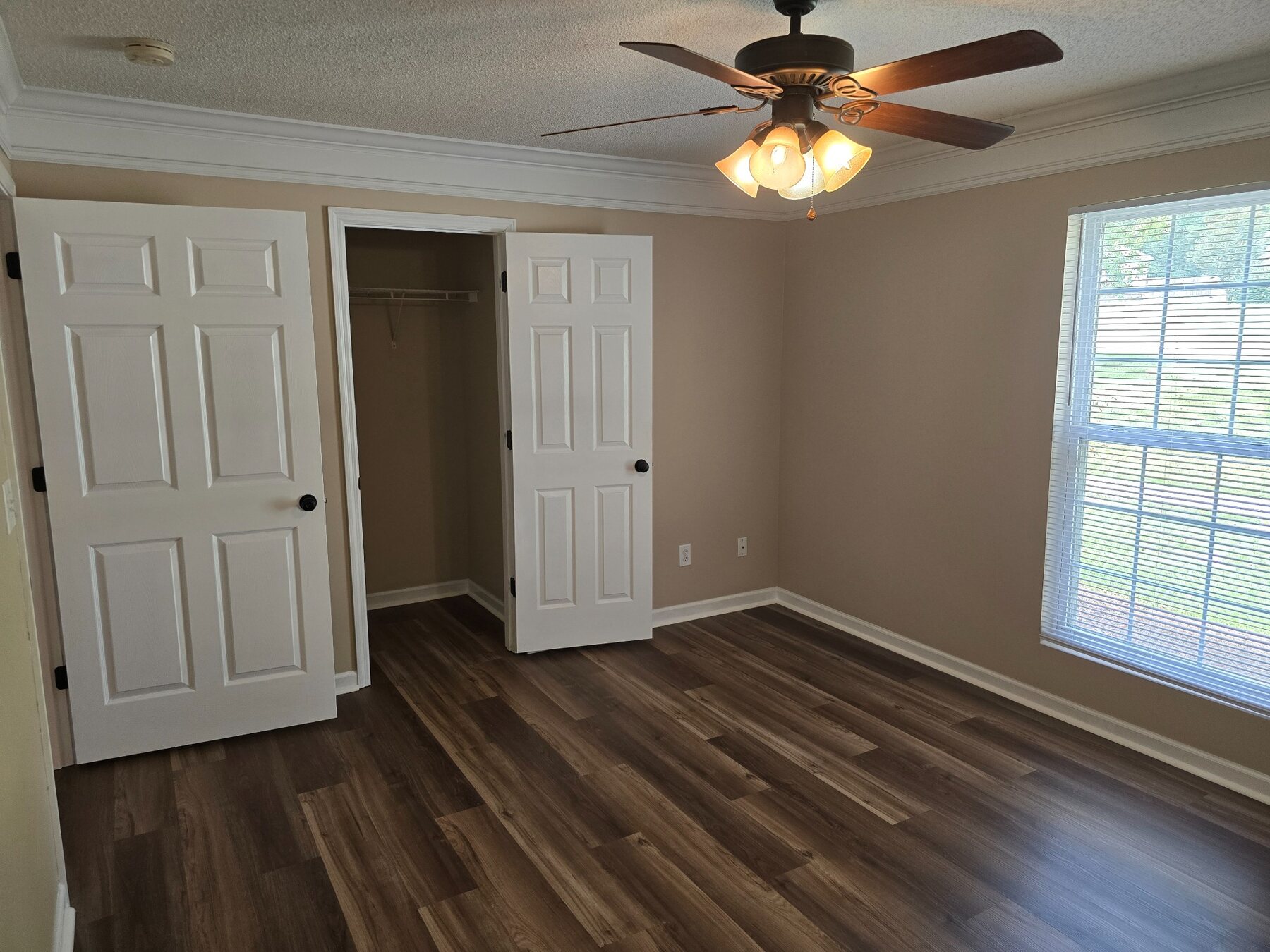 Bedroom with ceiling fan, wide window, and two closets