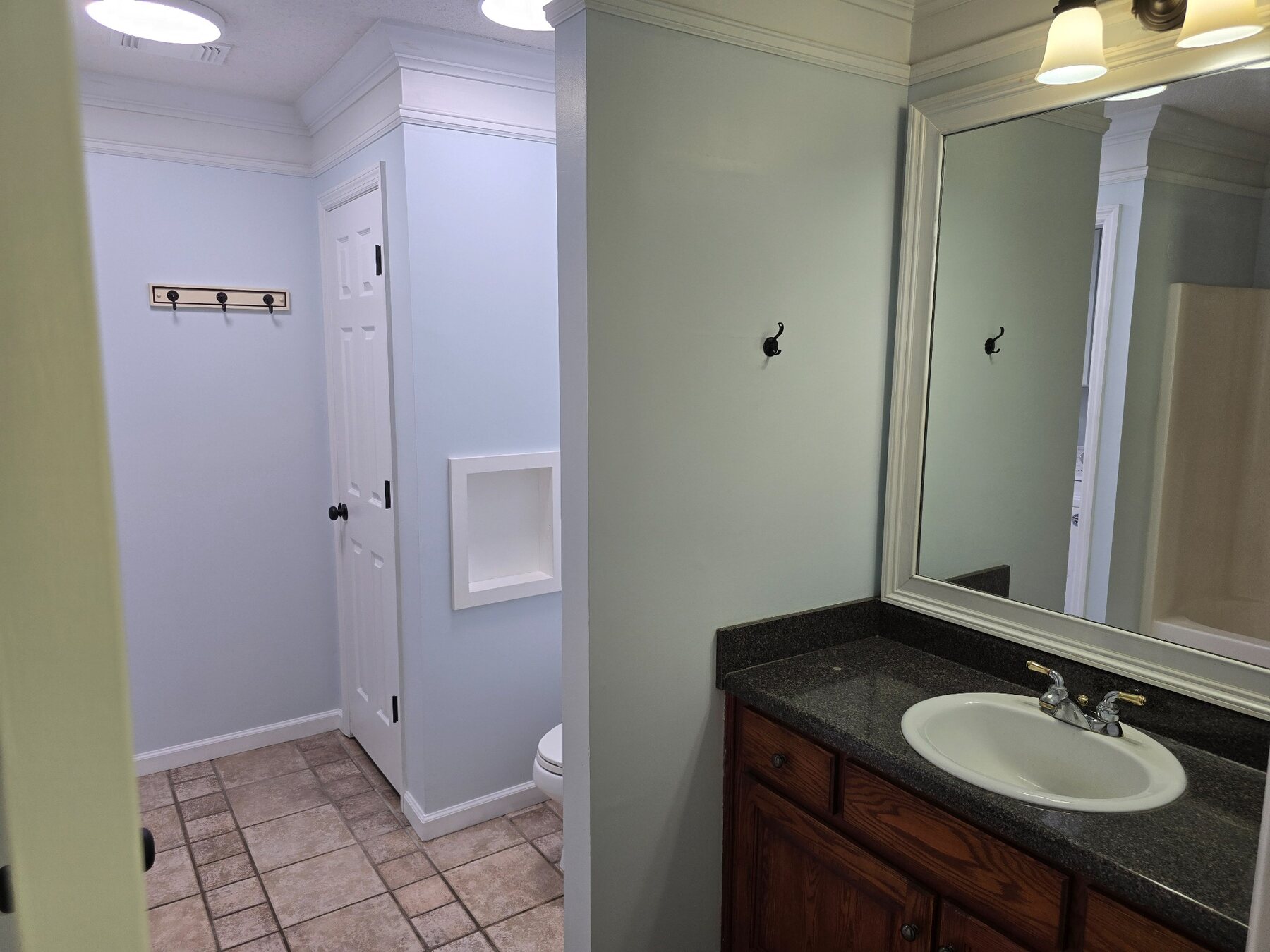 Bathroom vanity with dark countertop, large mirror, and tiled floor