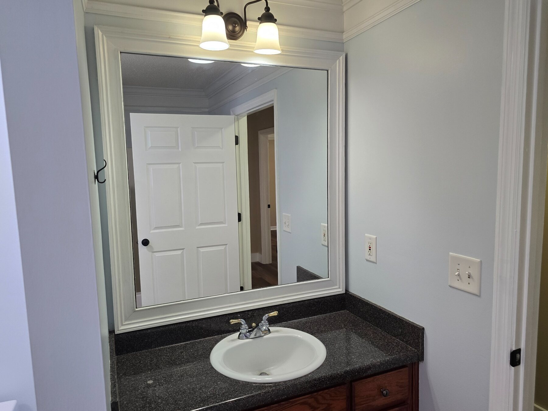 Bathroom vanity with dark countertop and framed mirror
