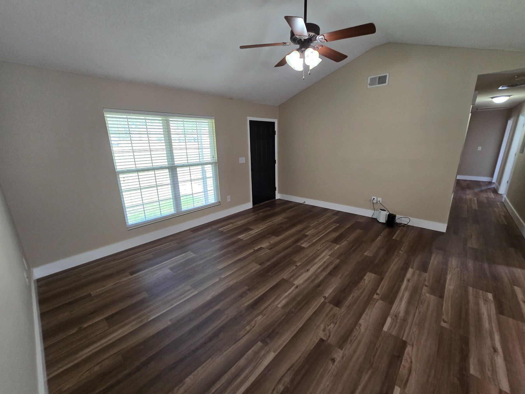 Living room with wide window, ceiling fan, and hard-surface flooring