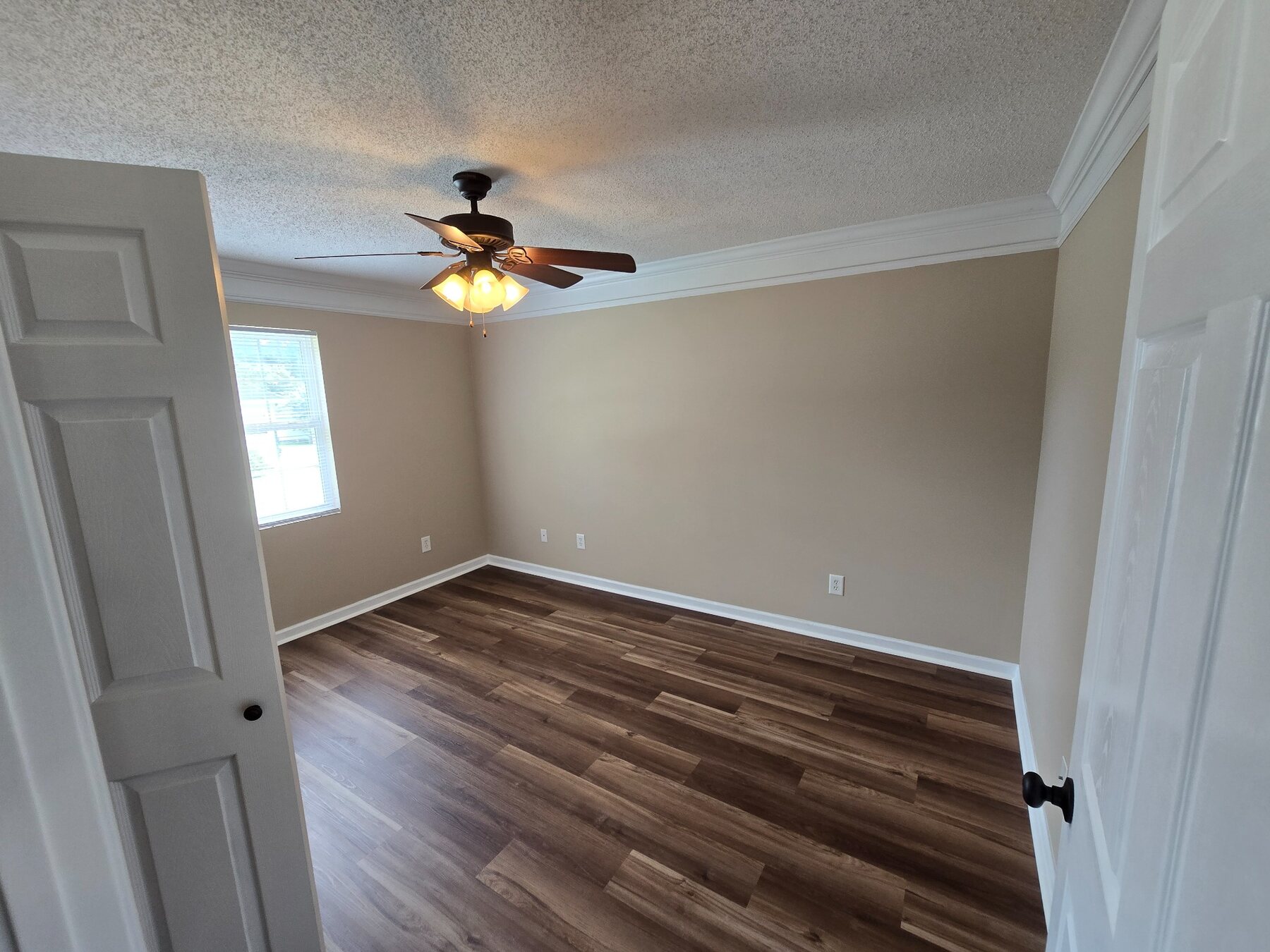 Bedroom viewed from the doorway with ceiling fan and window