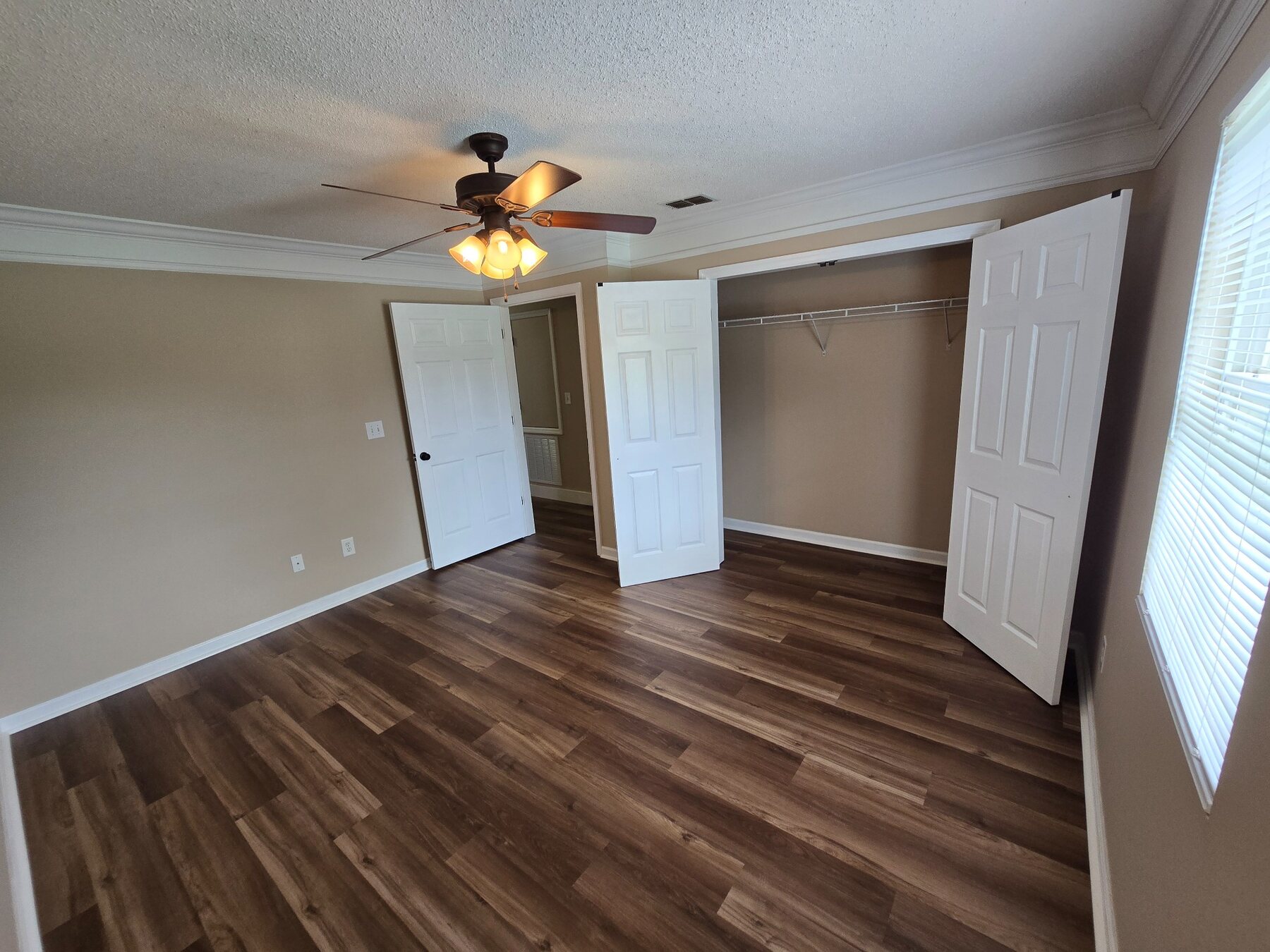 Bedroom with wide window and open double-door closet